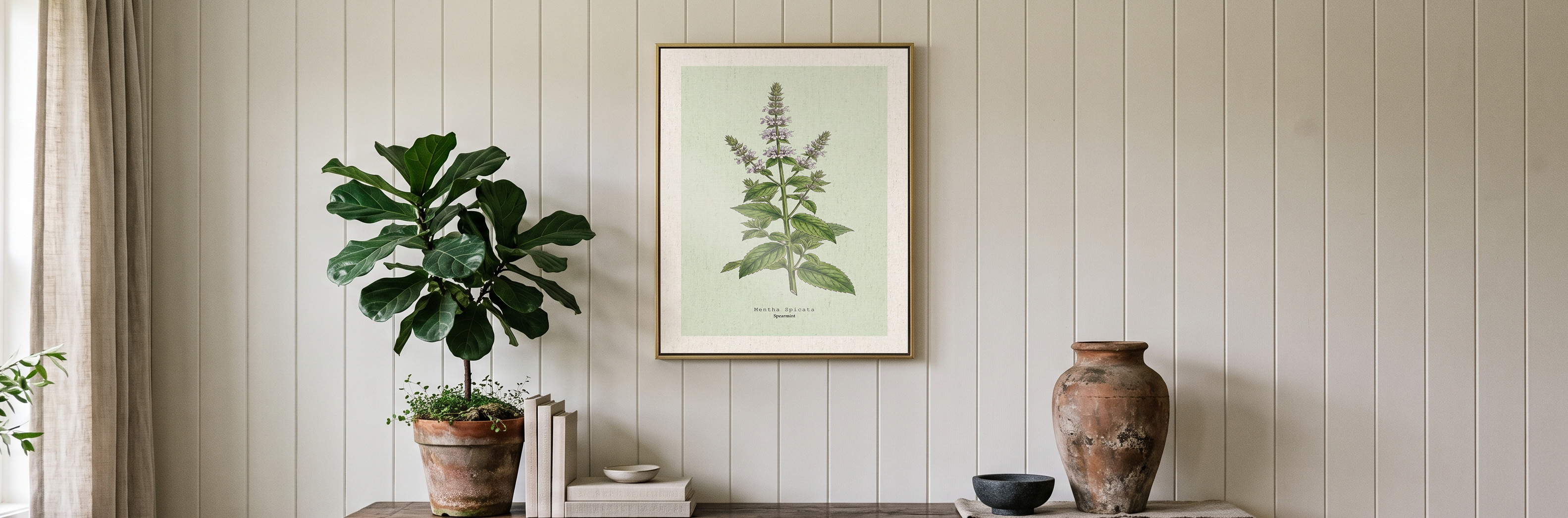 A framed print on a panelled wall between a leafy plant and a terracotta urn